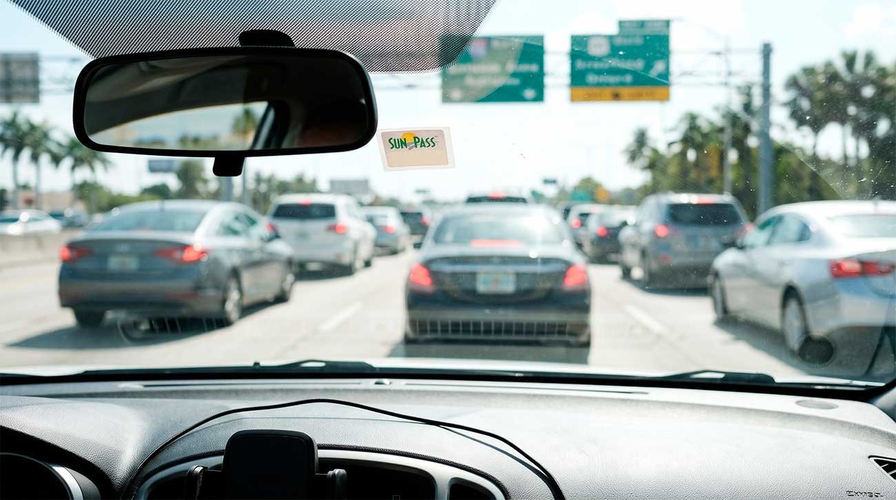 Navigating heavy Miami highway gridlock using a SunPass sticker to avoid rental car toll fees.